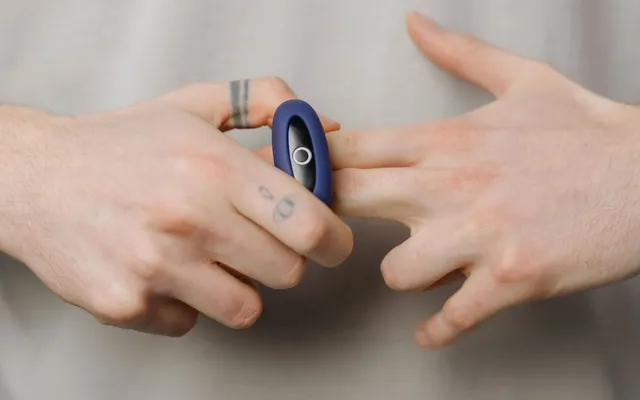 Bague anti stress en acier inoxydable portée sur un doigt, gros plan lumineux sur fond neutre